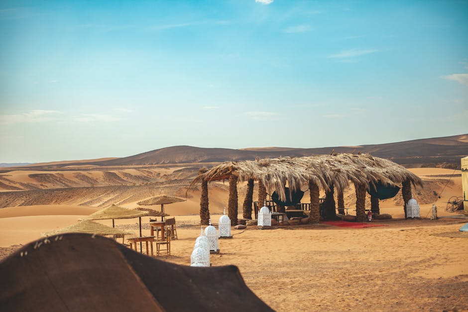 Captured in Morocco's Merzouga, this desert oasis features a traditional rustic shelter amidst sand dunes.