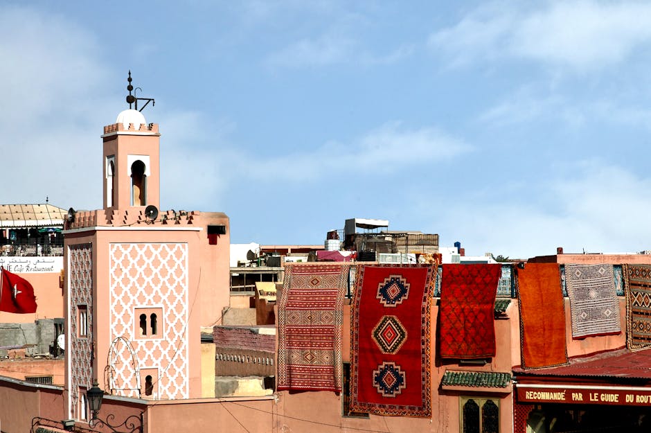 Colorful Moroccan rugs on a rooftop with traditional architecture in Marrakech, Morocco.