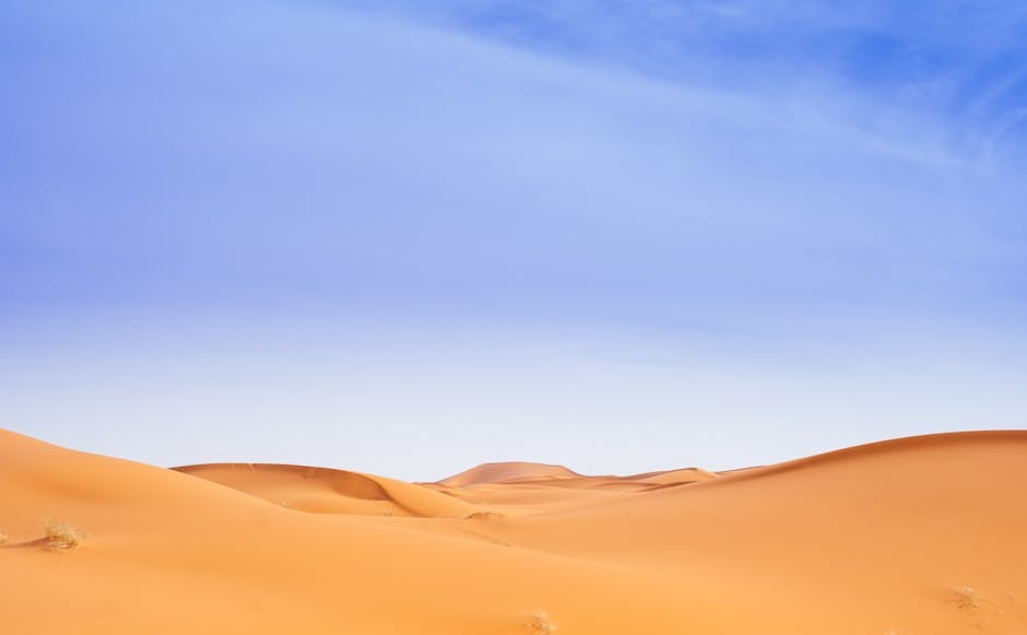 Stunning view of golden sand dunes in Merzouga, Morocco under a clear blue sky.